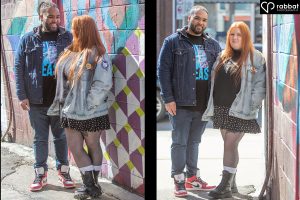 Engagement photos in Kensington Market. Two vertical side by side photos of a couple in front of a colourful mural with purple and turquoise. Woman is wearing a jean jacket, short skirt and black boots with white socks. Man is wearing a jean jacket, T-shirt and jeans. Man is Black and woman Metis with a light complexion and red hair..
